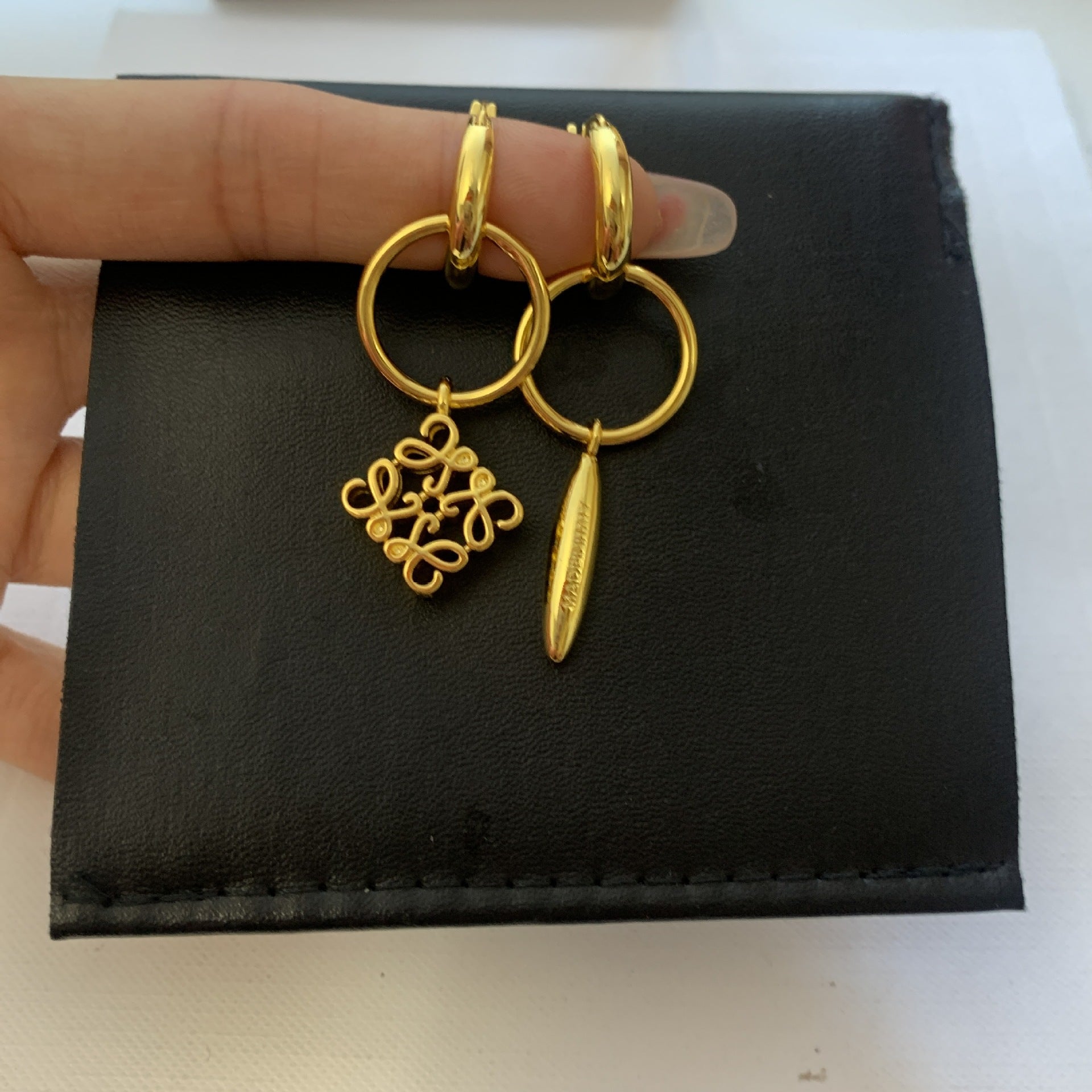 Clean shot of both earrings side-by-side on a plain background, clearly displaying the asymmetric design—one solid, one negative space.