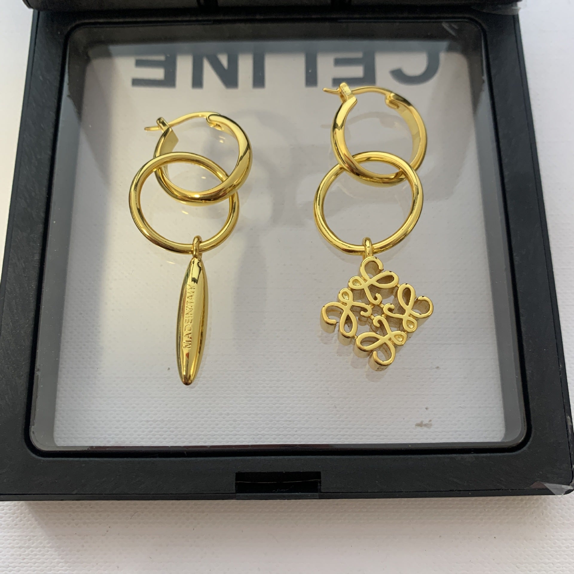 Clean shot of both earrings side-by-side on a plain background, clearly displaying the asymmetric design—one solid, one negative space.