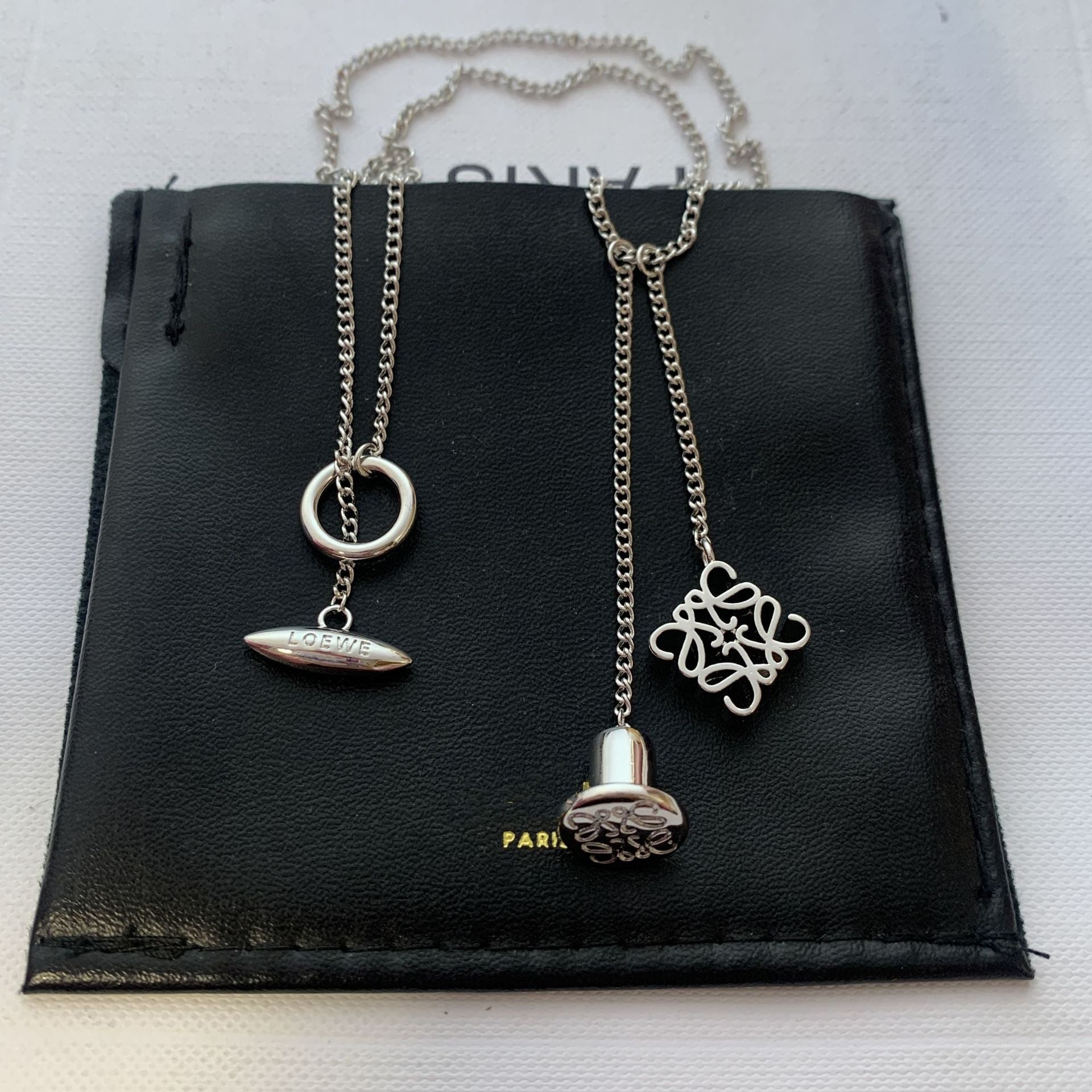  Clean, direct shot of the necklace on a plain background, clearly showcasing the Anagram charm and the fine chain.