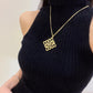 The necklace draped over a folded knit sweater or on a vanity next to a Loewe candle, reinforcing its association with cozy luxury and modern style.