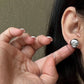  A soft-focus close-up of the earrings being worn, emphasizing their understated, elegant presence on the earlobe.