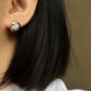  A soft-focus close-up of the earrings being worn, emphasizing their understated, elegant presence on the earlobe.