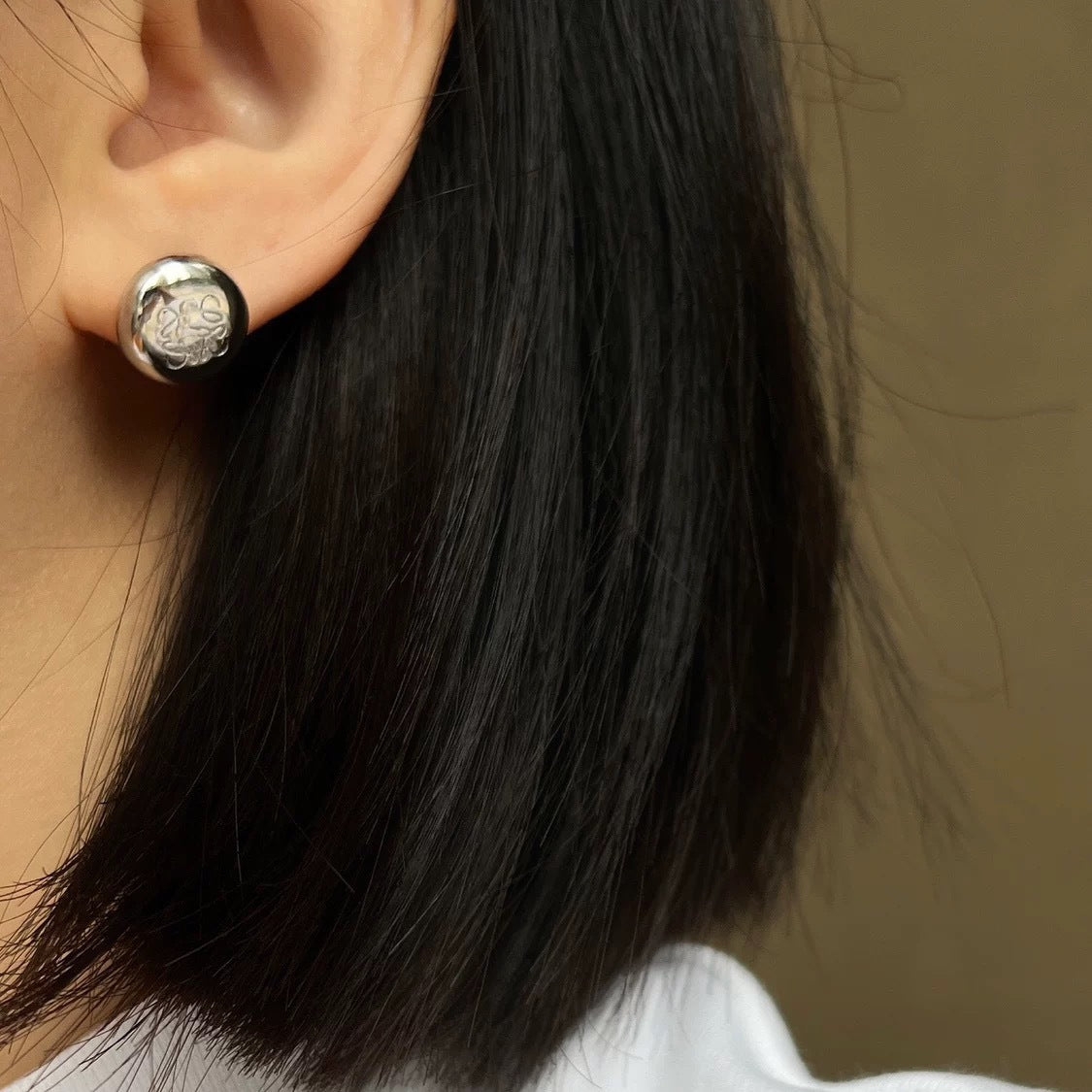  A soft-focus close-up of the earrings being worn, emphasizing their understated, elegant presence on the earlobe.