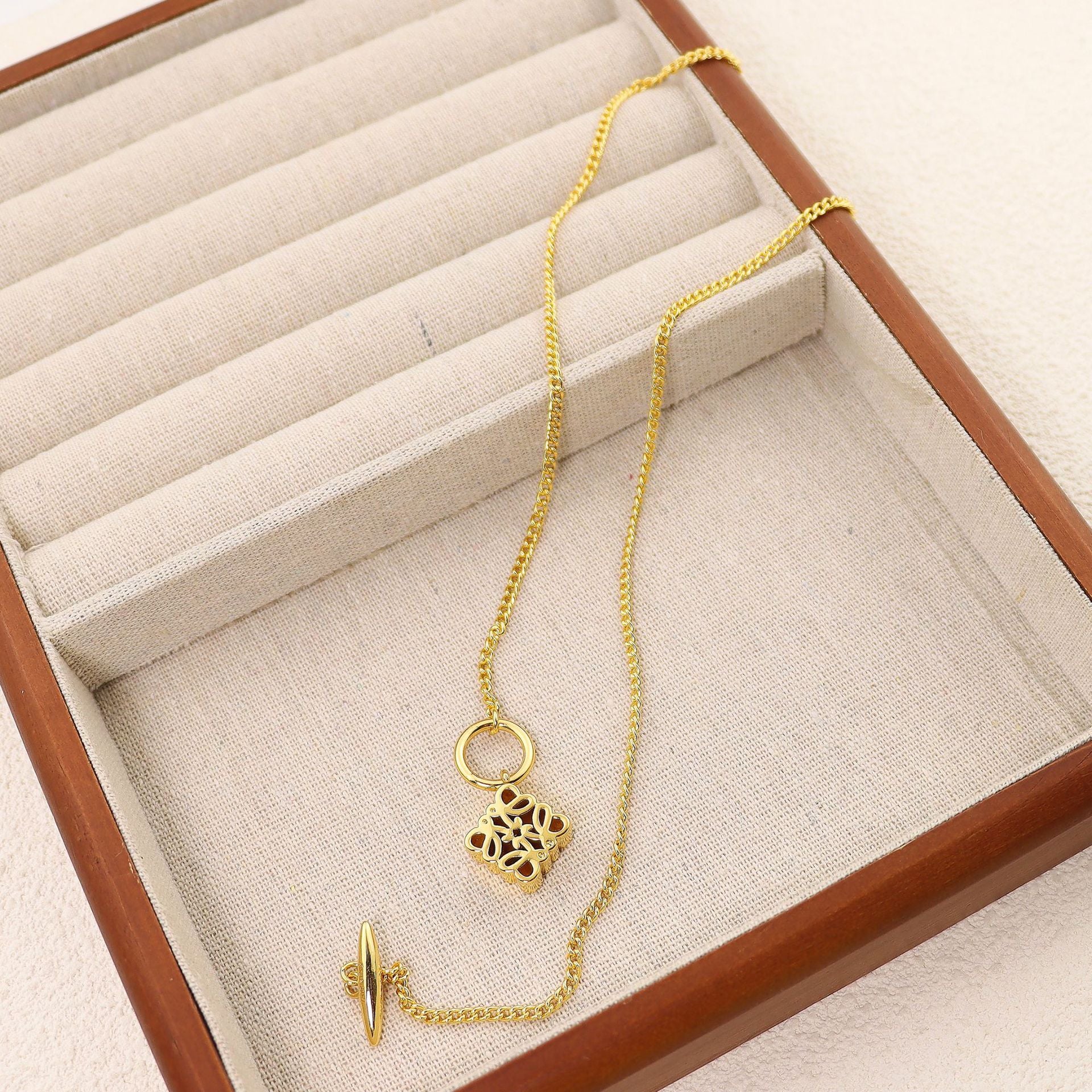Clean, crisp shot of the necklace laid flat or worn, against a solid neutral background, focusing on the iconic pendant.