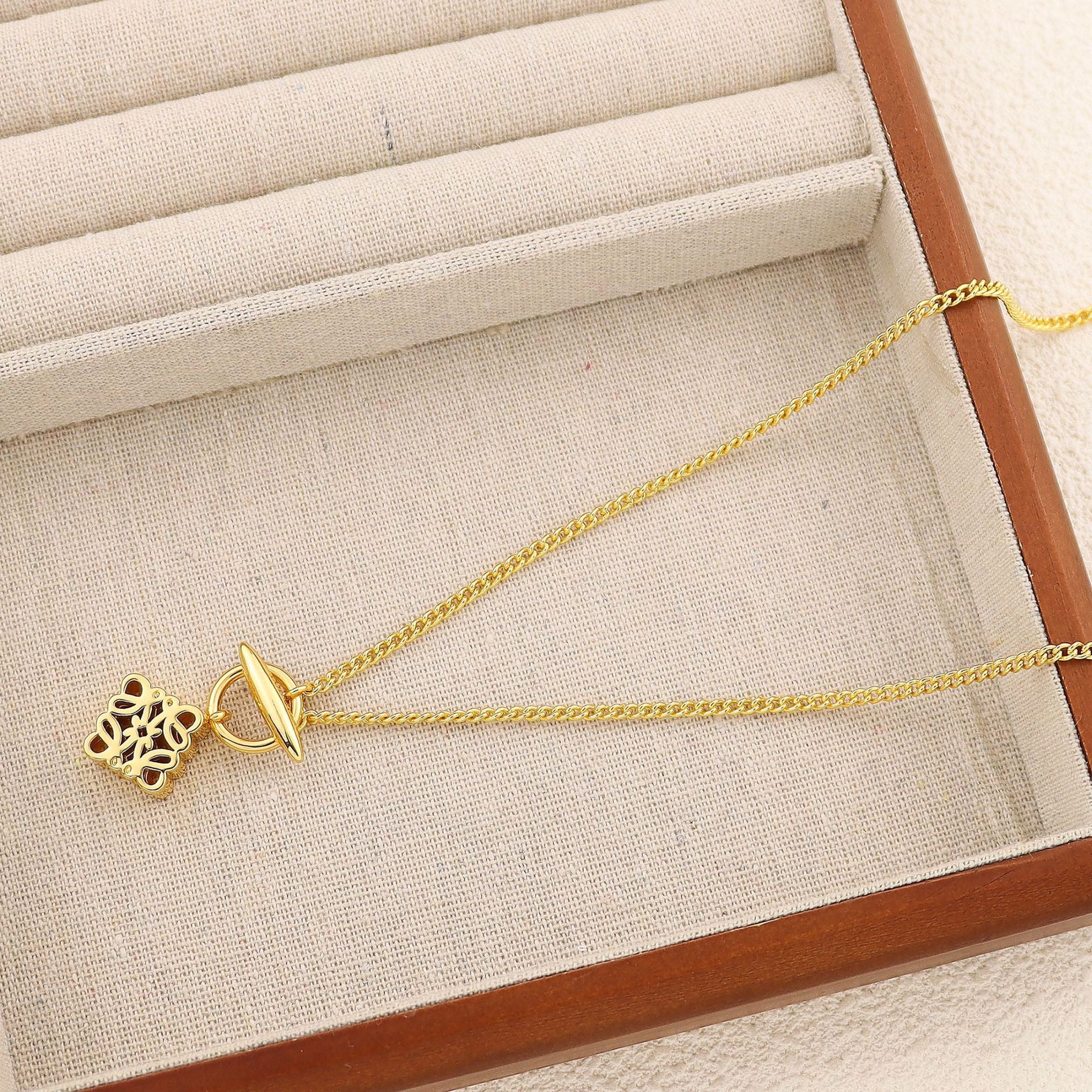 Clean, crisp shot of the necklace laid flat or worn, against a solid neutral background, focusing on the iconic pendant.
