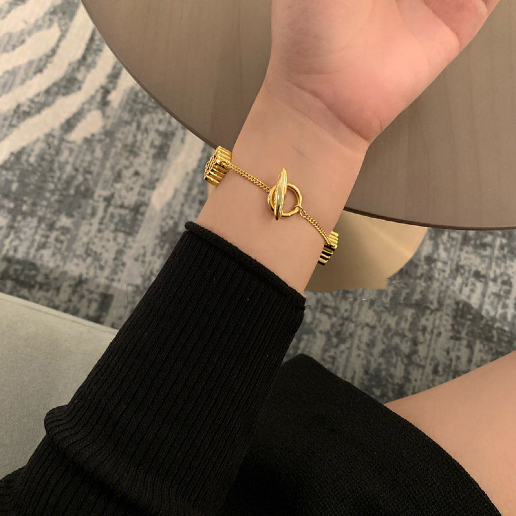 The bracelet displayed on a pedestal or next to a modern sculpture/architectural model, reinforcing its status as a piece of collectible design art.