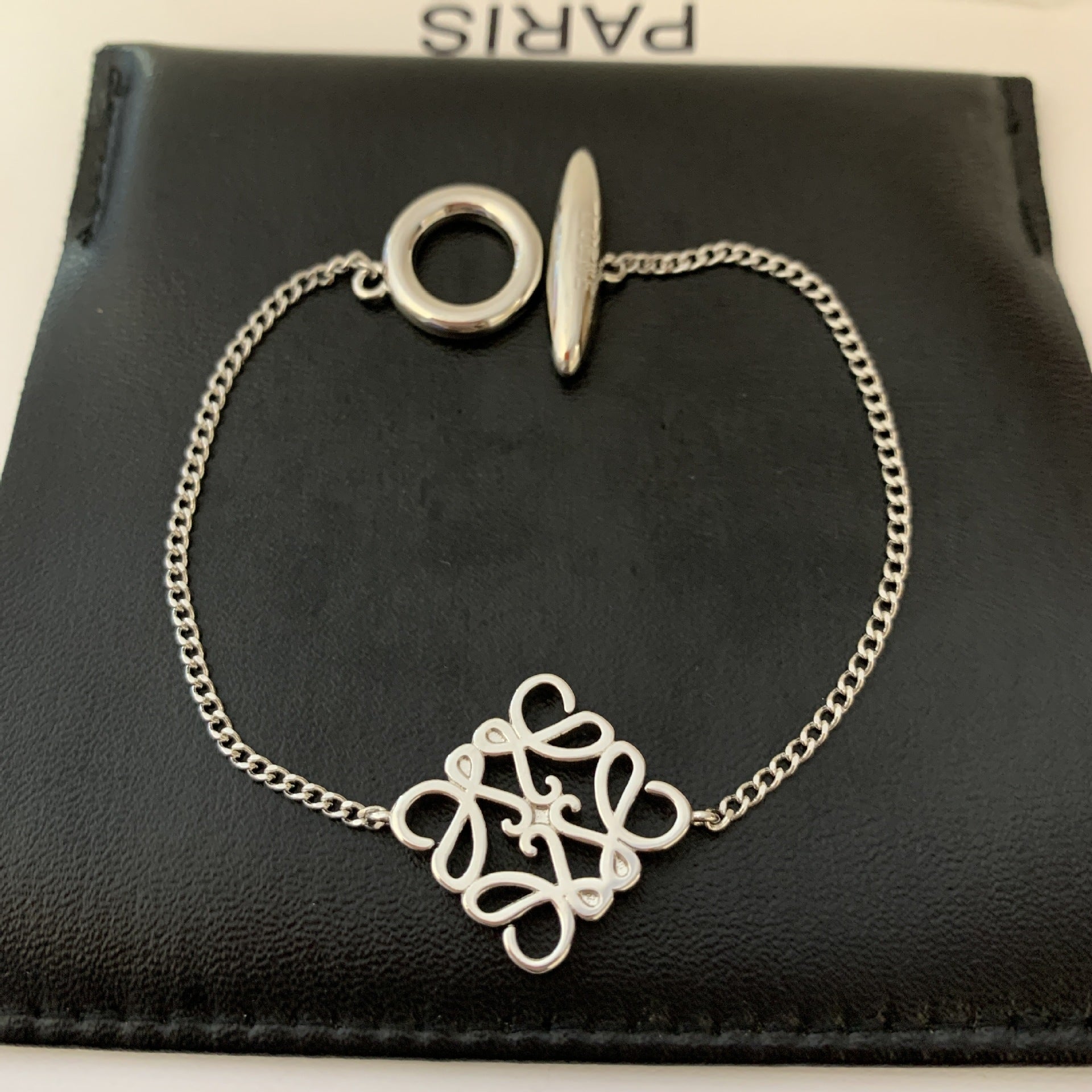 Artistic shot of the bangle isolated on a neutral background, highlighting its unique 3D geometric form and the hollow OT clasp.