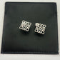 Clean, direct shot of a single earring against a neutral background, highlighting the smooth rhombus shape and the intricate openwork logo.