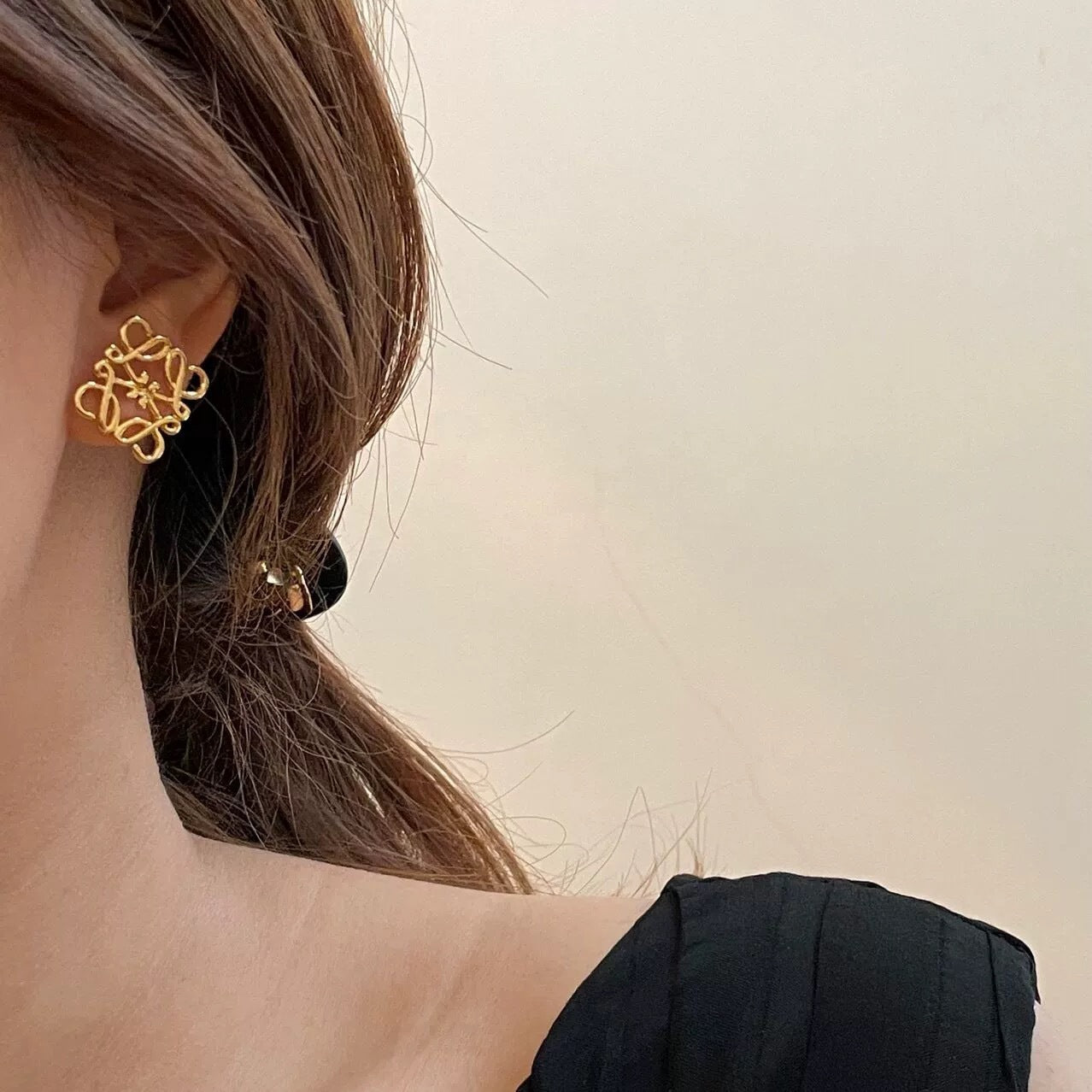 An editorial close-up of the earrings being worn, emphasizing their modern, architectural appeal against the skin.