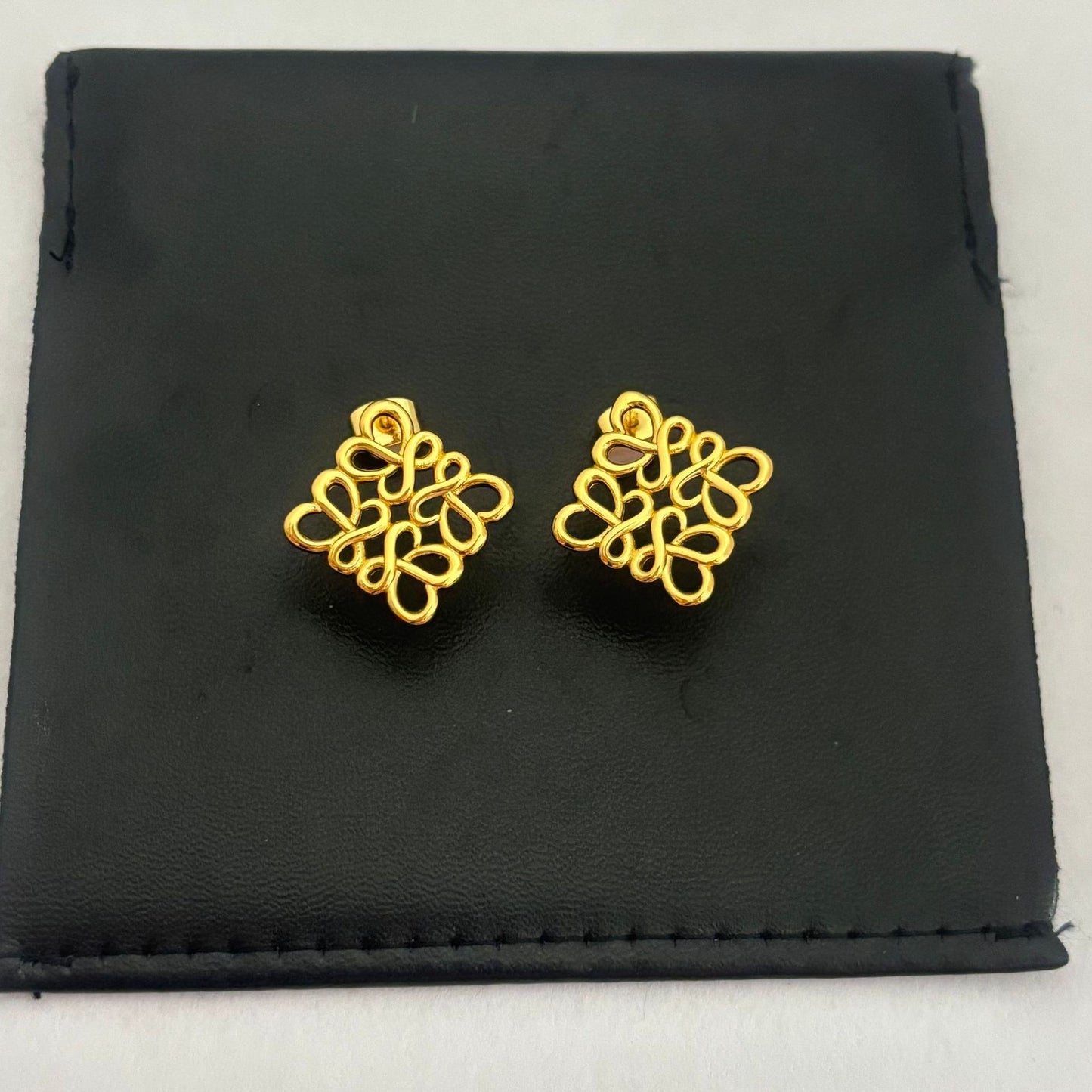 Clean, direct shot of a single earring against a neutral background, highlighting the smooth rhombus shape and the intricate openwork logo.