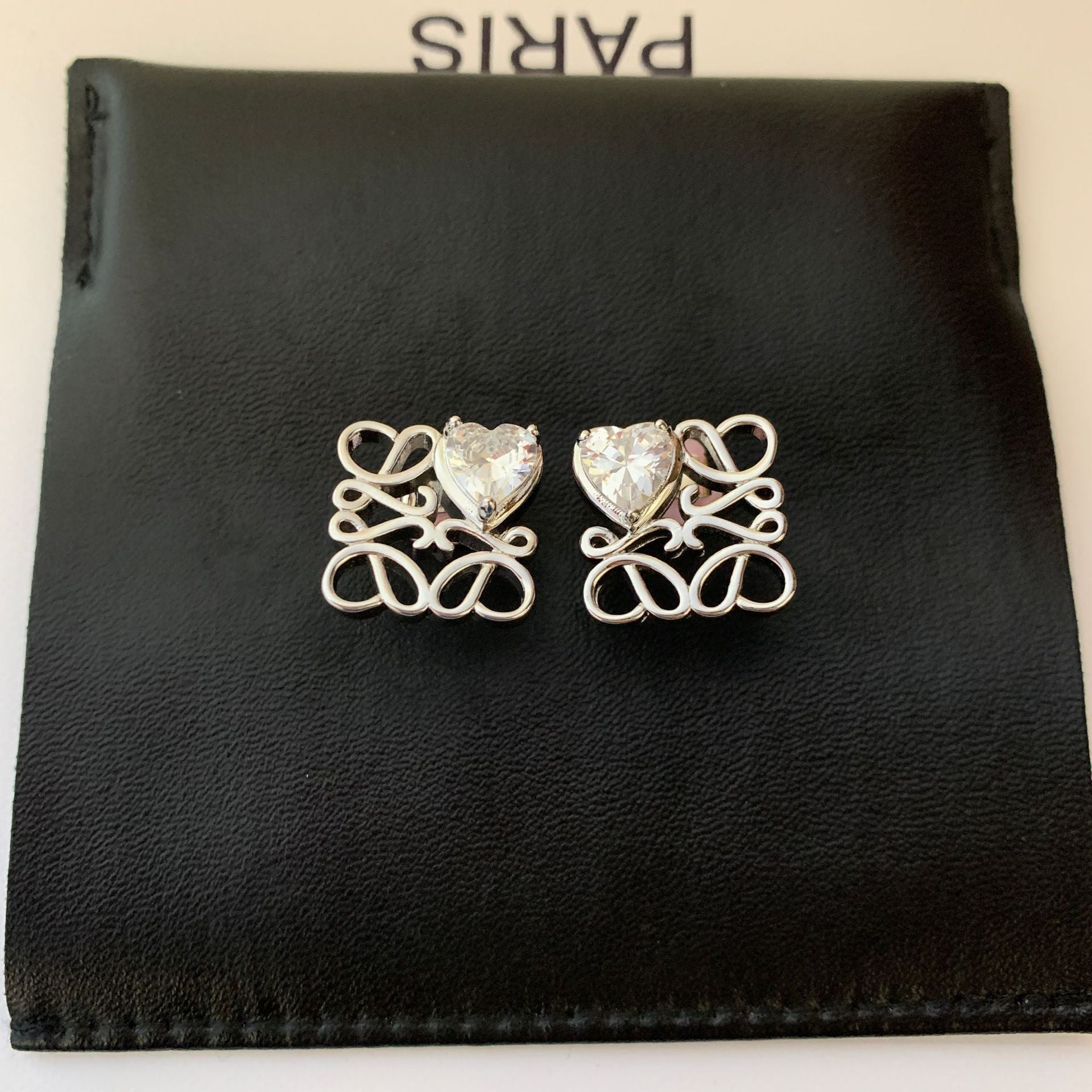  Clean, front-facing shot of a single earring against a neutral background, clearly showcasing the interlocking heart design.