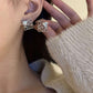 The earrings placed next to a simple line drawing of two hearts or on a page of poetry, reinforcing the themes of love and meaningful design.