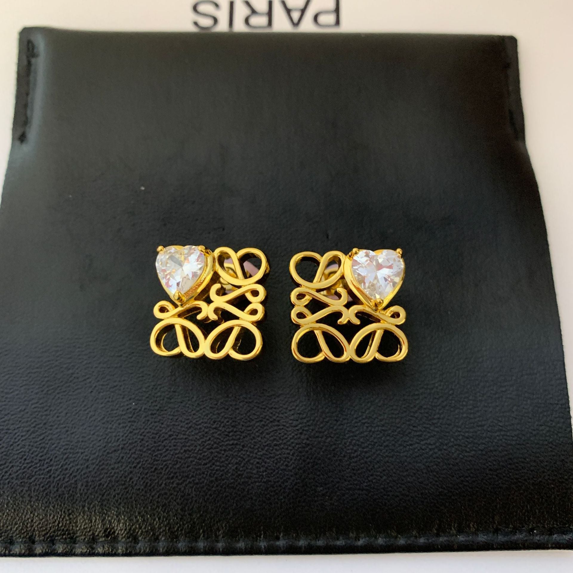  Clean, front-facing shot of a single earring against a neutral background, clearly showcasing the interlocking heart design.