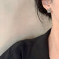 A fashion-forward North American woman wearing the earrings with a minimalist outfit (e.g., crisp white shirt or solid-color top). Focus on how the earrings add interest without overpowering.