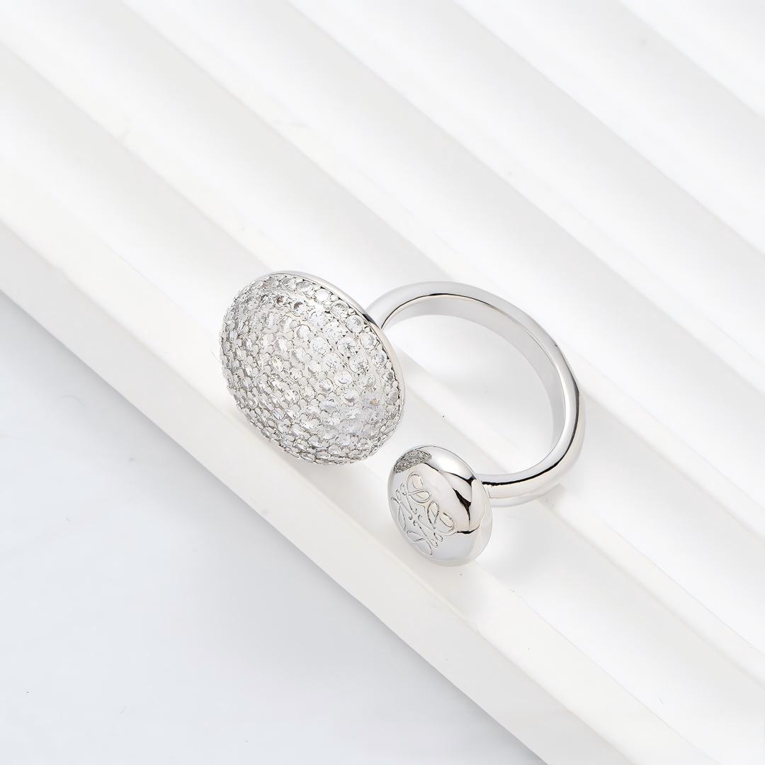 Clean, angled shot of the ring on a finger or stand, showcasing the square silhouette and intricate hollow pattern against a solid background.