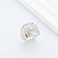 Clean, angled shot of the ring on a finger or stand, showcasing the square silhouette and intricate hollow pattern against a solid background.