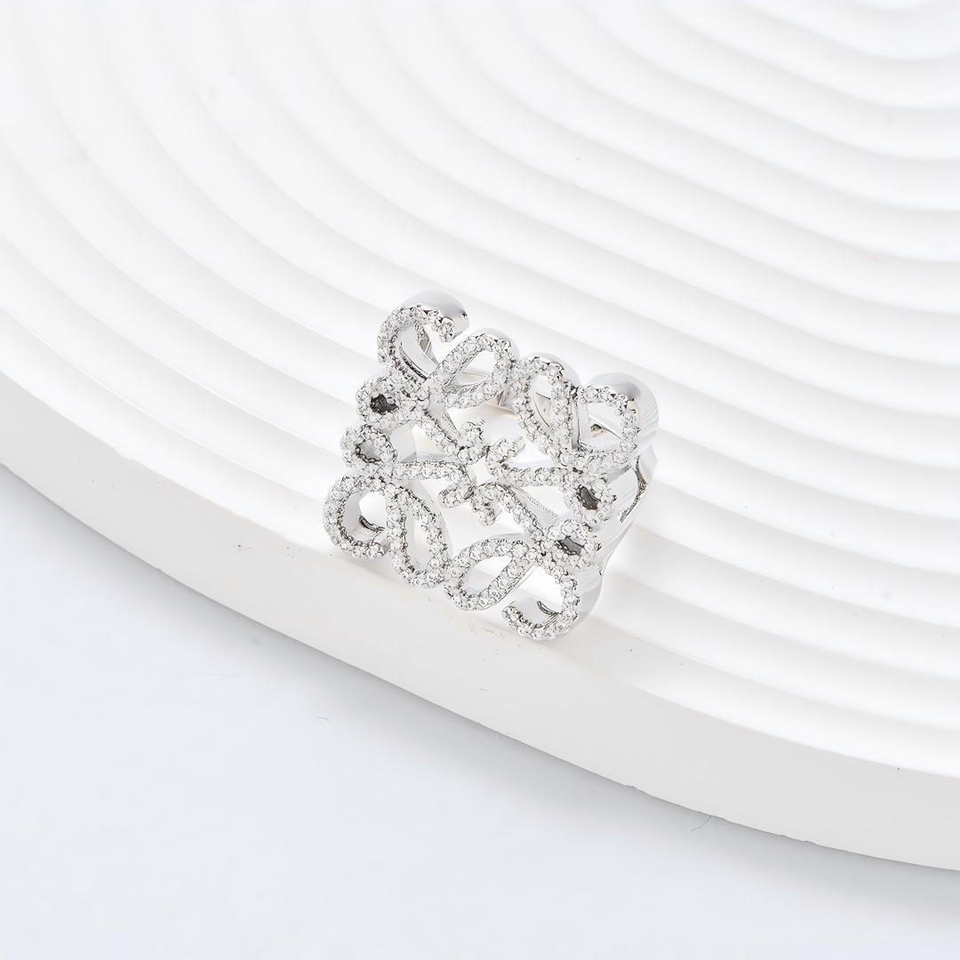Clean, angled shot of the ring on a finger or stand, showcasing the square silhouette and intricate hollow pattern against a solid background.