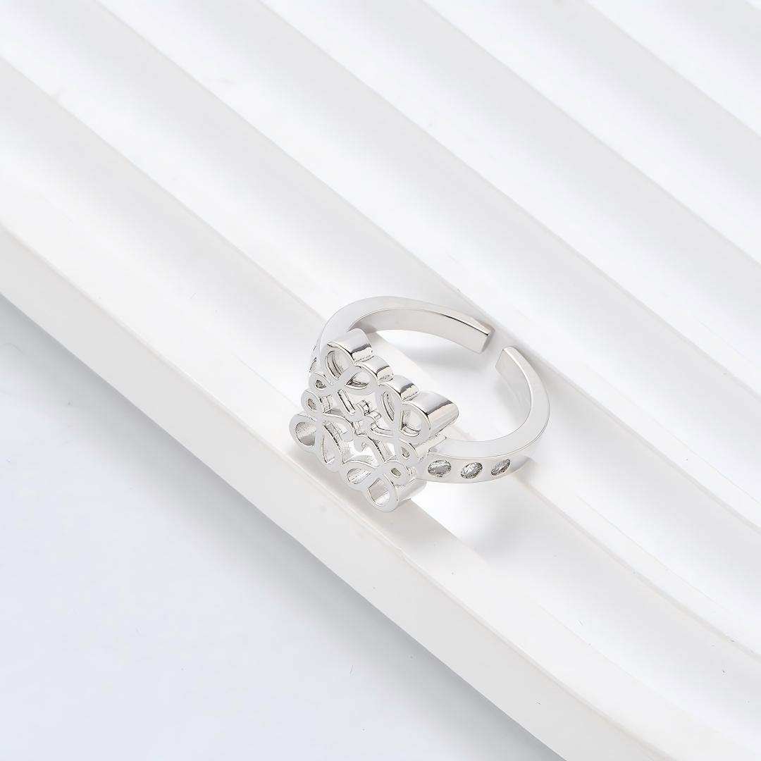 Clean, angled shot of the ring on a finger or stand, showcasing the square silhouette and intricate hollow pattern against a solid background.