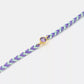Bracelet with purple and green braided design and a purple gemstone on a white background