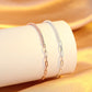 Two gold bracelets on a white cylindrical object with a gold background