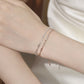 Two delicate bracelets on a wrist against a neutral background