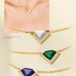 Gold necklaces with triangular gemstones on a beige background