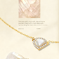 Gold necklace with a heart-shaped white stone pendant on a beige background