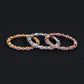 Three diamond bracelets in gold, silver, and rose gold on a black background