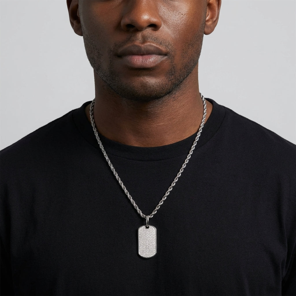  Man in a simple white tee and bomber jacket, the chevron tag resting at the collarbone — clean, sharp, understated.