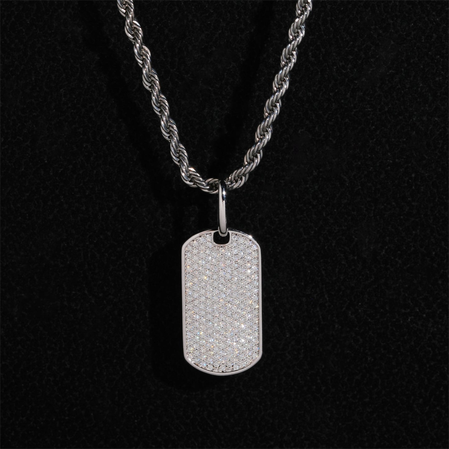 Clean white or light gray background — the chevron tag displayed on a bust form or flat surface. The geometric chevron shape catches soft light, showing high polish or brushed finish, with diamond accents sparkling subtly along the design lines.
