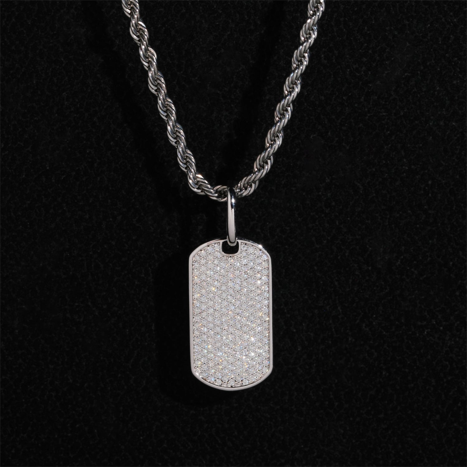 Clean white or light gray background — the chevron tag displayed on a bust form or flat surface. The geometric chevron shape catches soft light, showing high polish or brushed finish, with diamond accents sparkling subtly along the design lines.