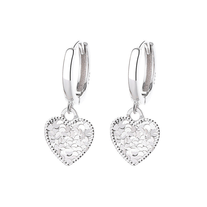Silver heart-shaped earrings with intricate designs on a white background