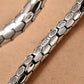 Silver bracelet with textured design on a beige background