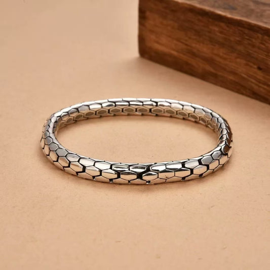 Silver bracelet with honeycomb pattern on a beige surface