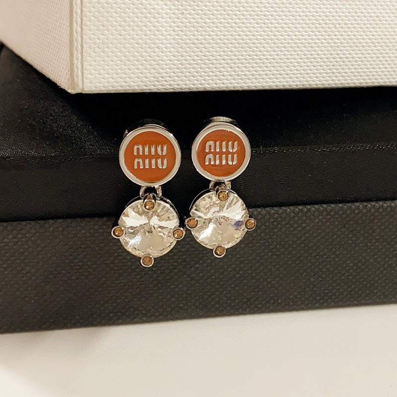 A bright, clean shot on a light grey or white background, showcasing the earrings' full shape and the sparkling contrast between metal and crystals. Alt text: "Miu Miu White Crystal and Metal Designer Earrings - Sparkling Statement Piece."
