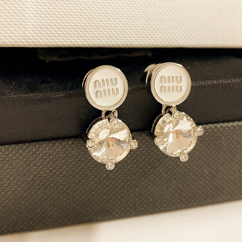 A bright, clean shot on a light grey or white background, showcasing the earrings' full shape and the sparkling contrast between metal and crystals. Alt text: "Miu Miu White Crystal and Metal Designer Earrings - Sparkling Statement Piece."