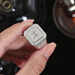 Silver ring with gemstones held by a hand against a dark background