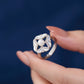 Silver ring with a pearl held by a hand against a dark blue background