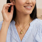 A close-up lifestyle shot of a woman wearing a delicate gold necklace with a small padlock and key pendant. The pendant features a light green enamel section.