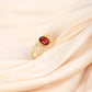 Gold ring with a red gemstone on a beige fabric background