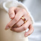 Close-up of a hand wearing a gold ring with a red gemstone, brand 'YAMAMORI' visible.