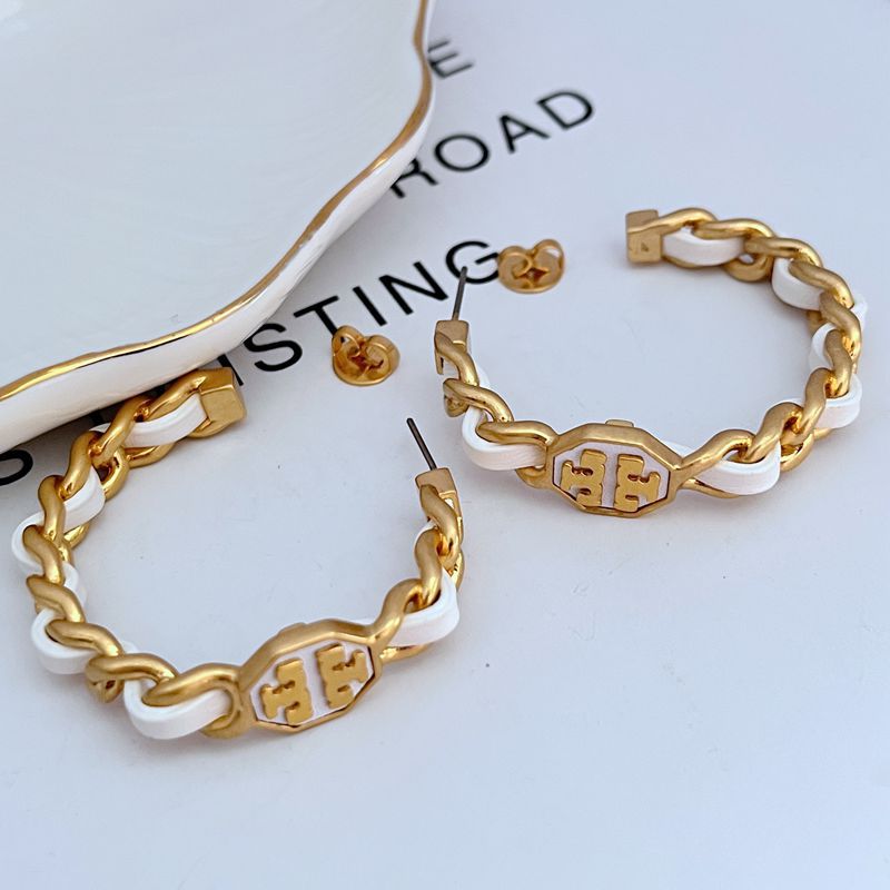 Both hoops displayed hanging or laid flat on a natural texture (like wood or linen), highlighting the leather and metal contrast.