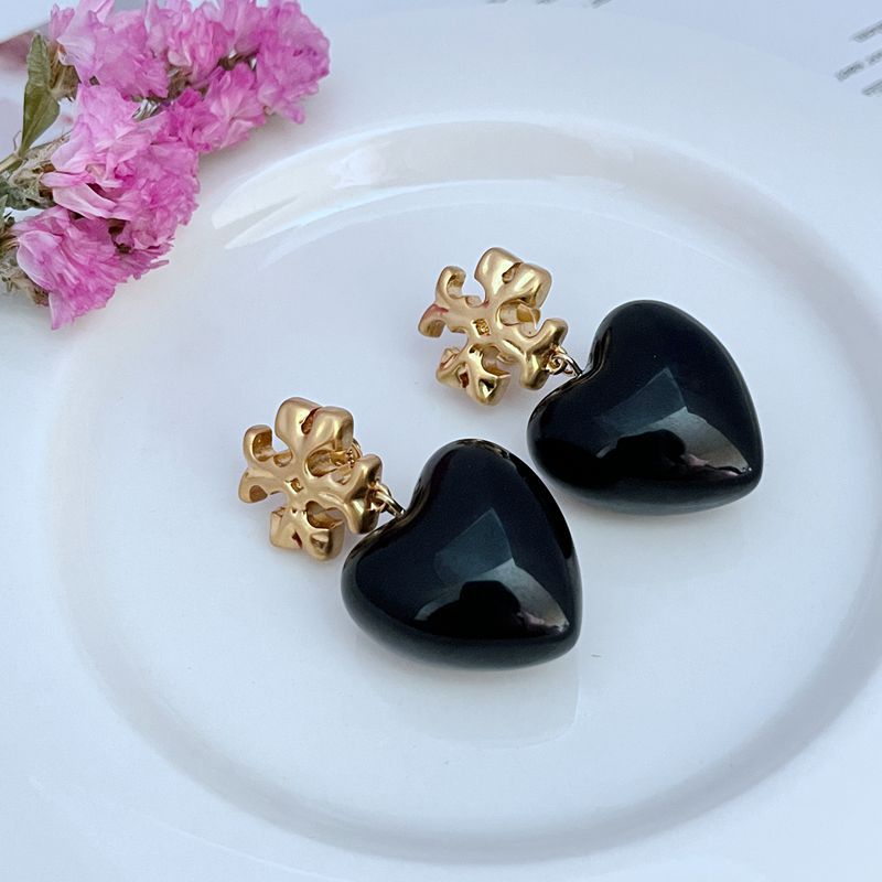 Both earrings displayed hanging against a soft, neutral background (like light gray or blush), highlighting the ivory heart and delicate chain.
