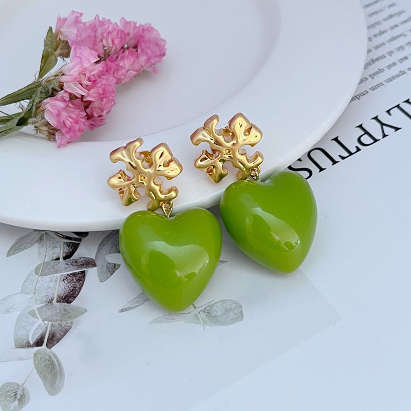 Both earrings displayed hanging against a soft, neutral background (like light gray or blush), highlighting the ivory heart and delicate chain.