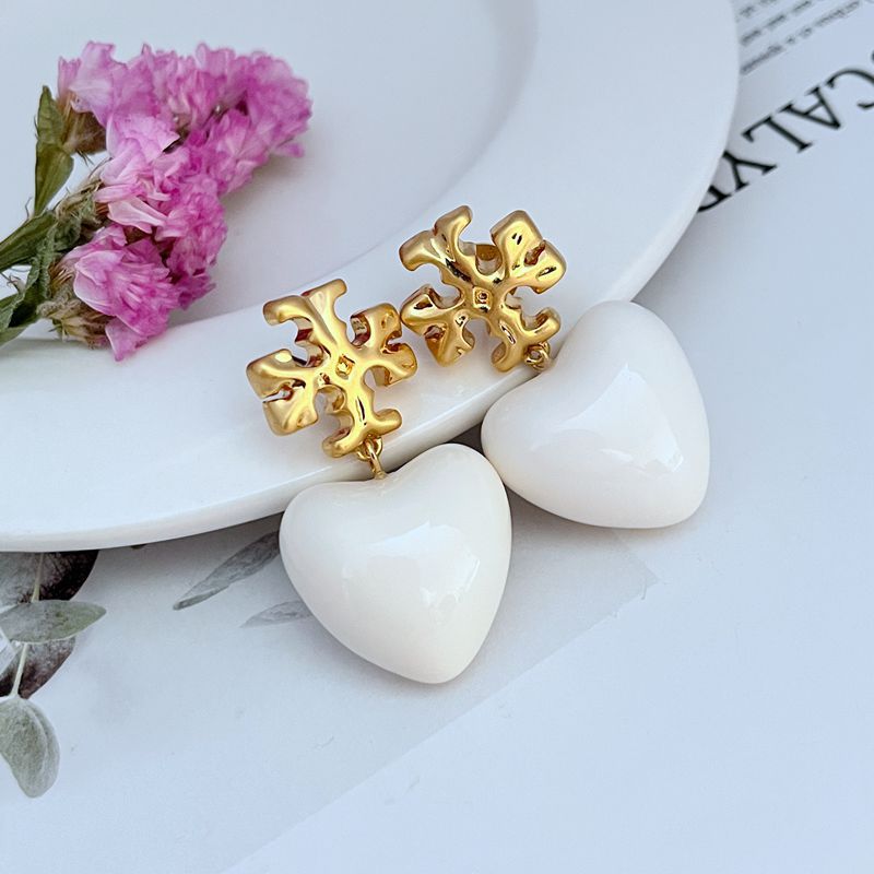 Both earrings displayed hanging against a soft, neutral background (like light gray or blush), highlighting the ivory heart and delicate chain.