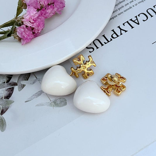 Both earrings displayed hanging against a soft, neutral background (like light gray or blush), highlighting the ivory heart and delicate chain.
