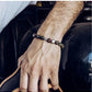 Hand wearing a beaded bracelet with a blurred background