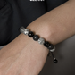 Bracelet with black and gray beads on a wrist, Zerra brand visible