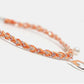 Close-up of a braided orange bracelet with silver accents on a white background