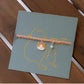 Cat-themed bracelet on a matching card with cat illustrations on a wooden surface